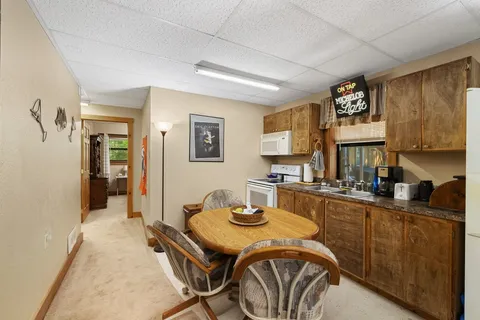 a kitchen with a stove a refrigerator a sink a dining table and chairs with wooden floor