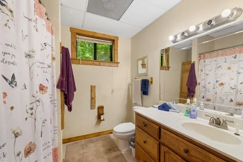 a bathroom with a granite countertop toilet a sink a mirror a shower curtain and a large mirror