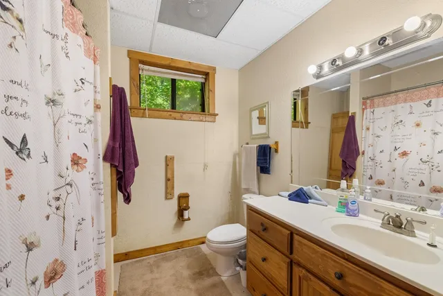 a bathroom with a granite countertop toilet a sink a mirror a shower curtain and a large mirror