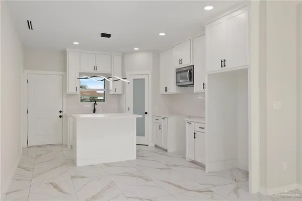 a view of a kitchen with refrigerator and white cabinets