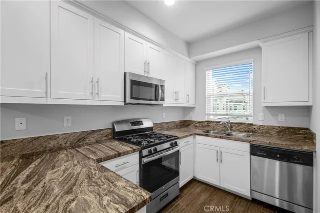 a kitchen with granite countertop white cabinets and appliances