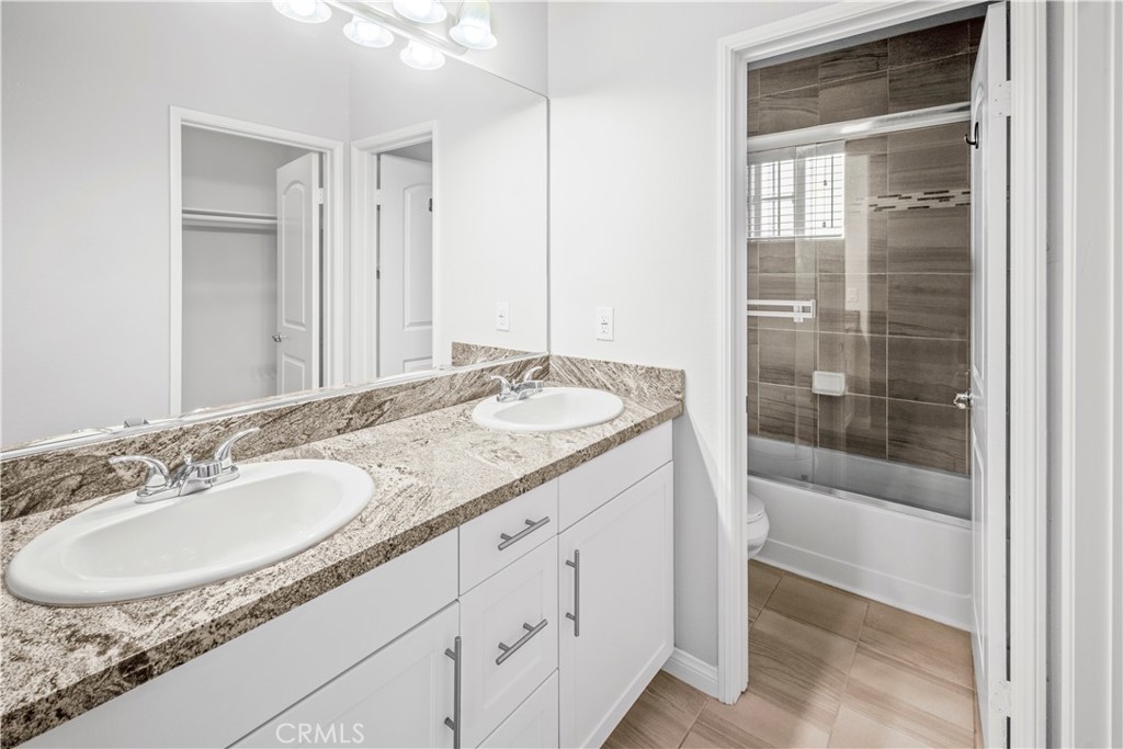 4617 Alekona Ct. Cypress, CA 90630 - Photo 26 of 35 a bathroom with a granite countertop sink a mirror and a bathtub