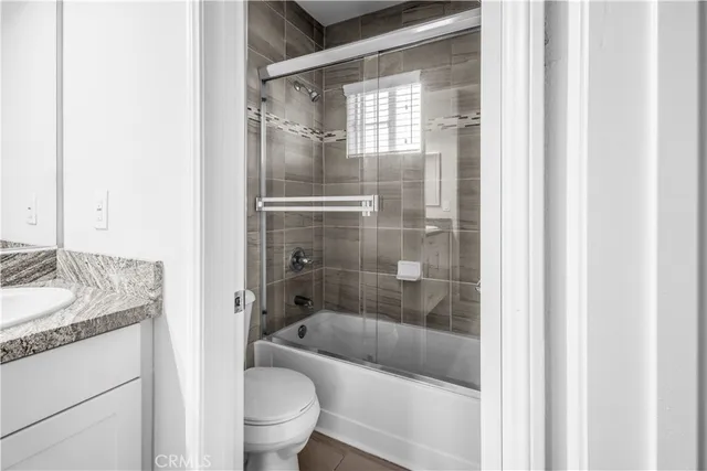 a bathroom with a granite countertop bathtub shower sink vanity and toilet