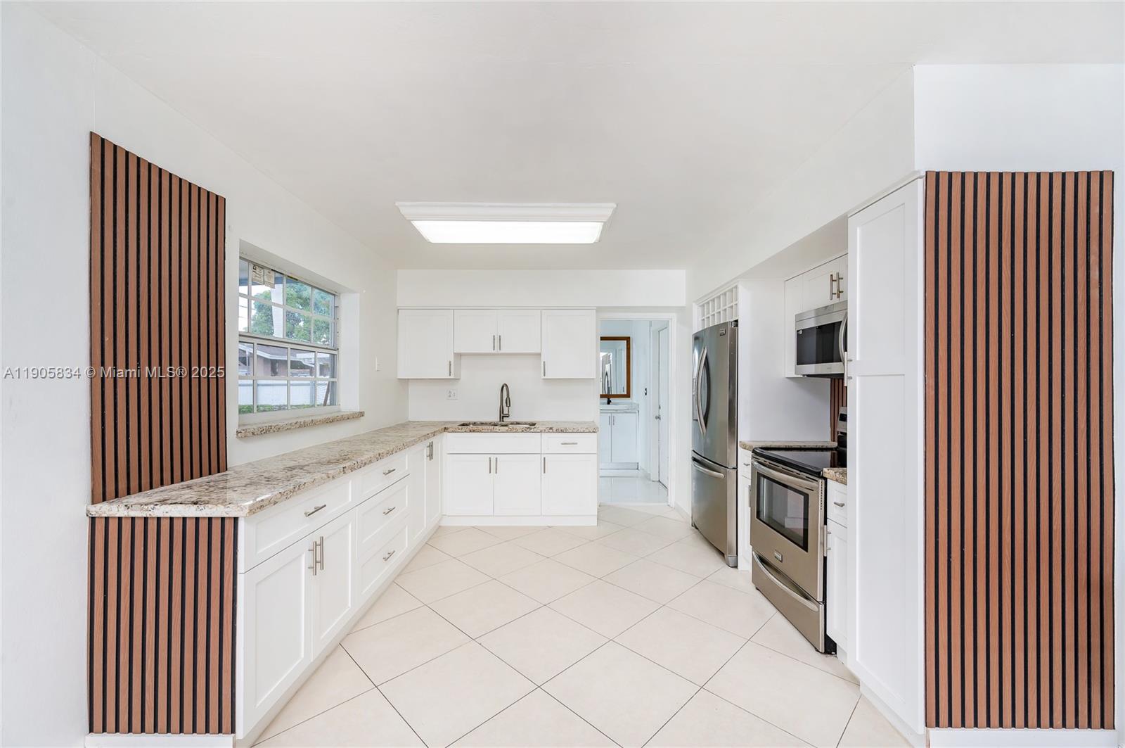 5420 Northwest 182nd Street Miami Gardens, FL 33055 - Photo 19 of 35 a kitchen with granite countertop white cabinets sink and stainless steel appliances