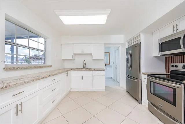 a kitchen with granite countertop white cabinets and white appliances