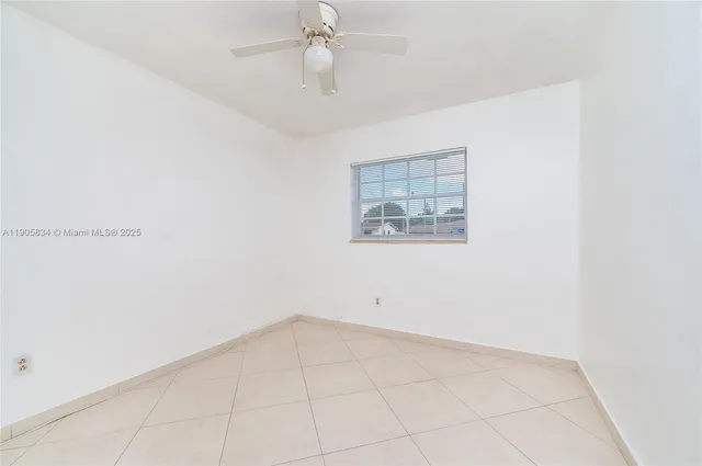 an empty room with white walls and ceiling fan
