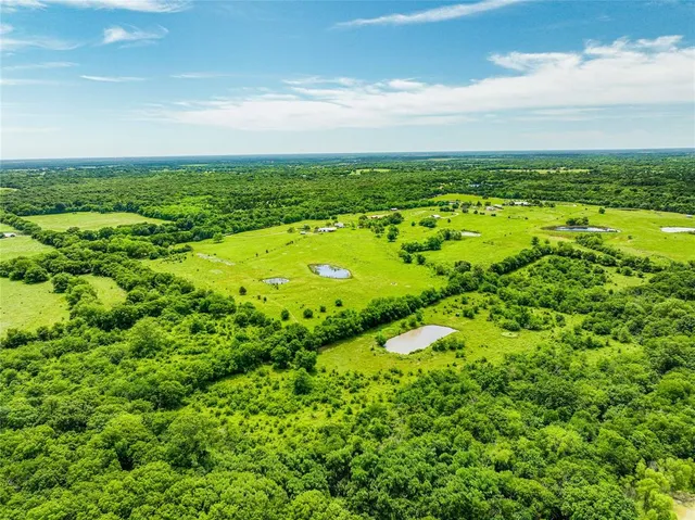 an aerial view of residential houses with outdoor space and trees all around