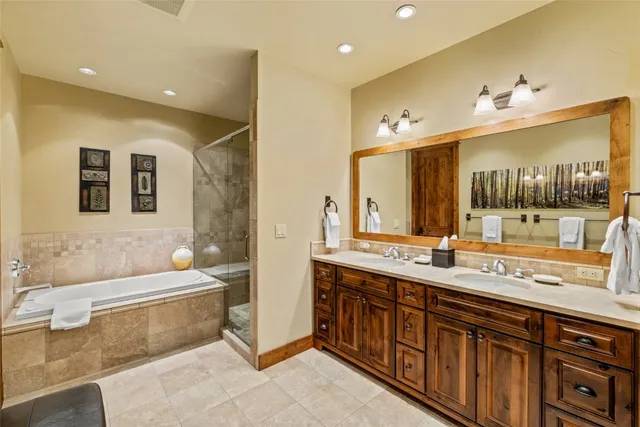 a spacious bathroom with a double vanity sink a mirror and a bathtub