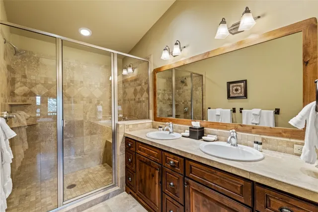 a bathroom with double vanity sinks and a shower