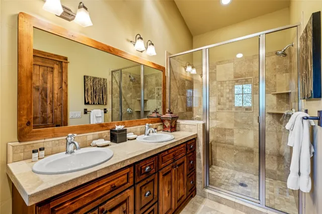 a bathroom with a double vanity sink mirror and shower