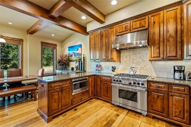 a kitchen with stainless steel appliances granite countertop a stove a sink dishwasher and cabinets with wooden floor