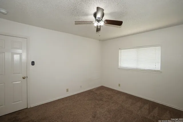 an empty room with a window and a fan