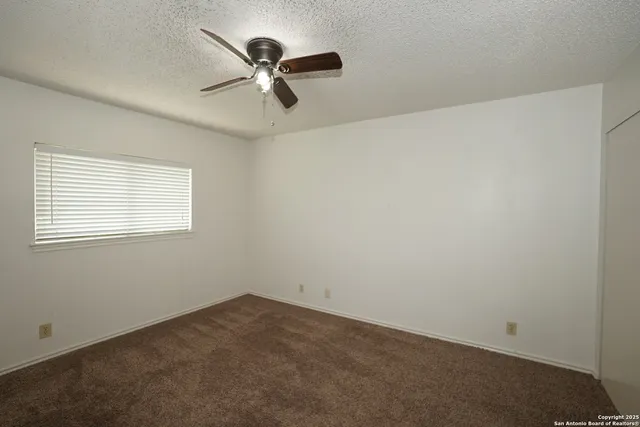 an empty room with a window and a fan