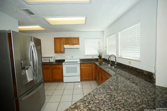 a kitchen with stainless steel appliances granite countertop a sink stove and refrigerator