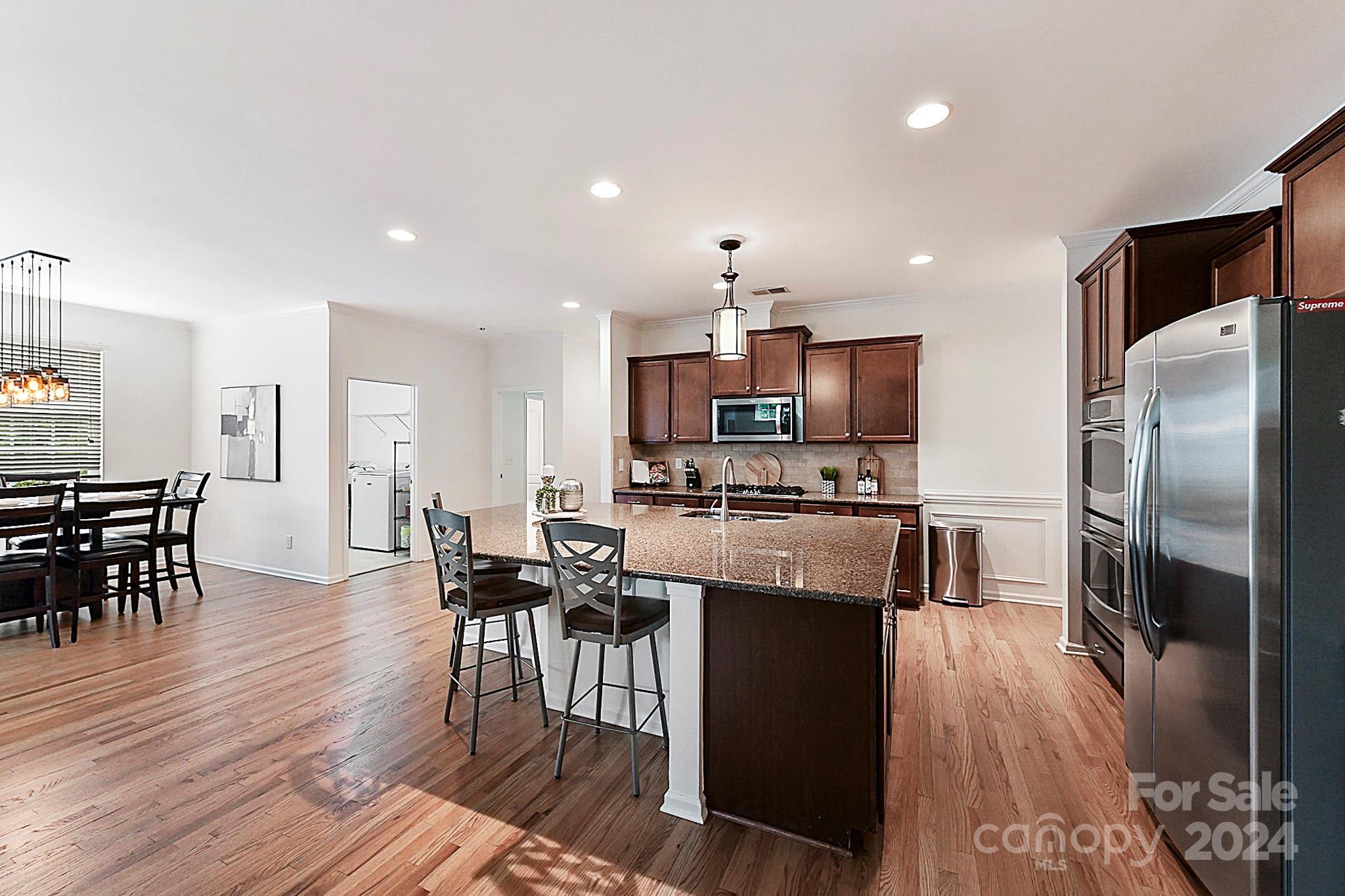 1201 Screech Owl Road Waxhaw, NC 28173 - Photo 11 of 43 a kitchen with stainless steel appliances a dining table chairs and wooden floor