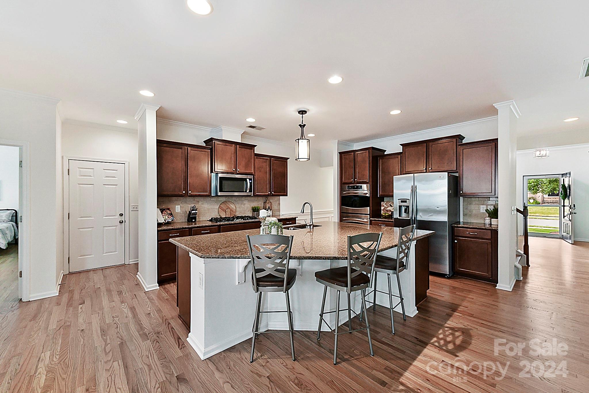 1201 Screech Owl Road Waxhaw, NC 28173 - Photo 12 of 43 a kitchen with stainless steel appliances a refrigerator a stove top oven a sink dishwasher and white cabinets with wooden floor
