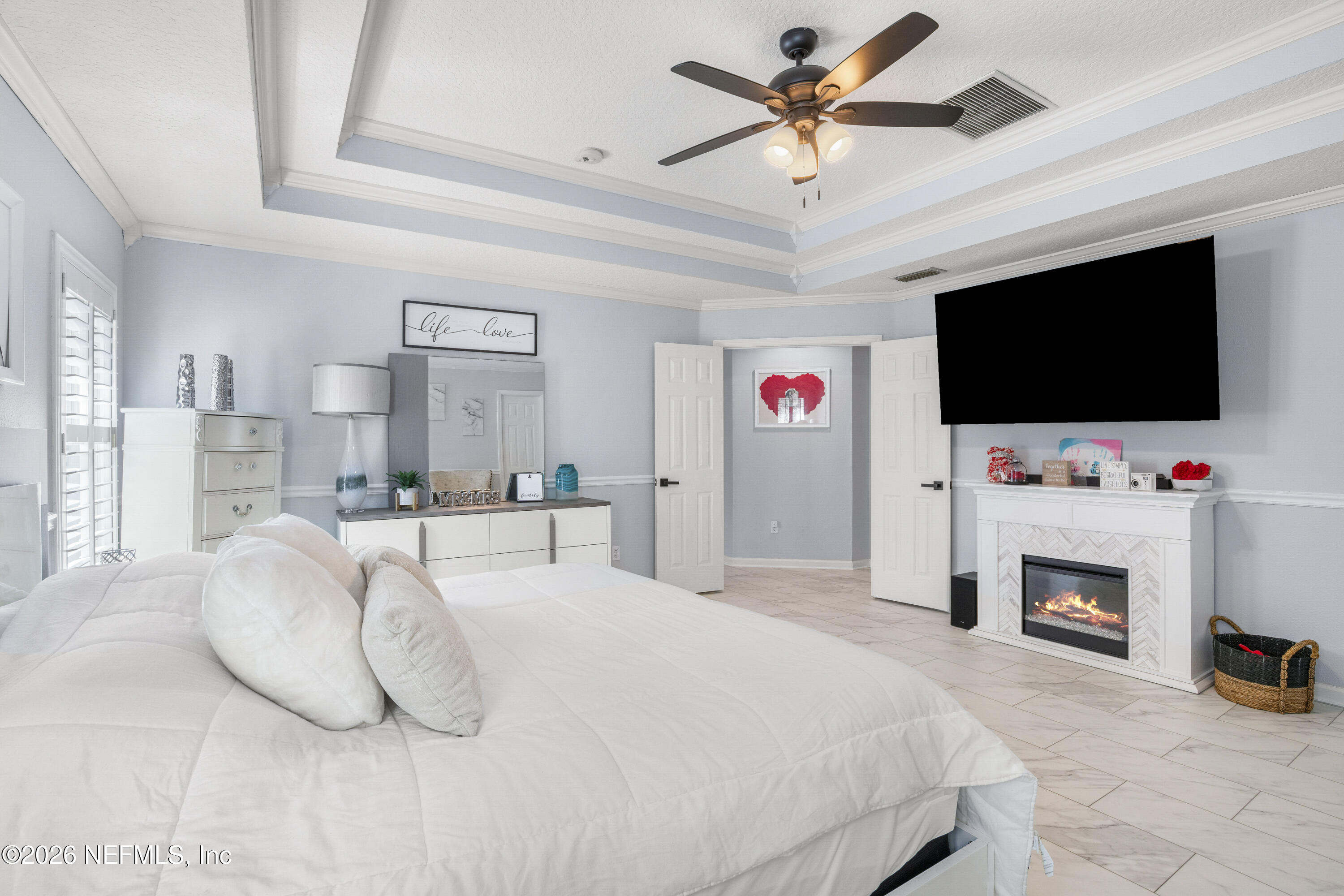 3020 South Atherley Road St. Augustine, FL 32092 - Photo 39 of 61 a bedroom with a bed a flat screen tv and a fireplace with a book shelf