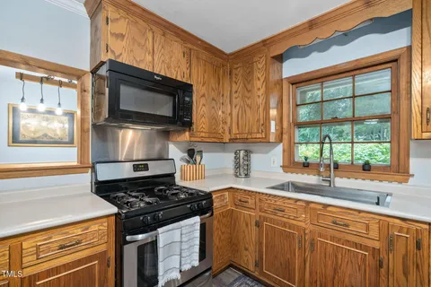 a kitchen with stainless steel appliances granite countertop a refrigerator a stove a sink dishwasher a dining table and chairs with wooden floor