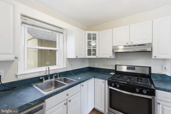 a kitchen with granite countertop stainless steel appliances a sink stove and cabinets