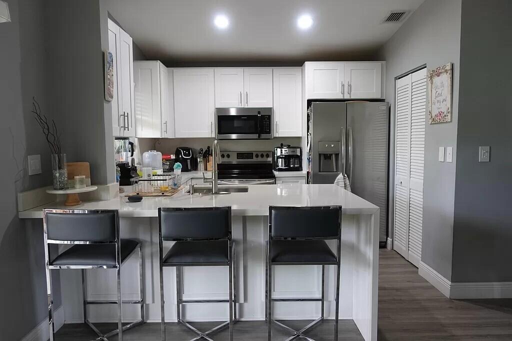 11720 Timbers Way Boca Raton, FL 33428 - Photo 7 of 19 a kitchen with stainless steel appliances kitchen island granite countertop a table chairs microwave and sink