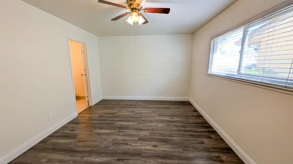 a view of an empty room with wooden floor and a window