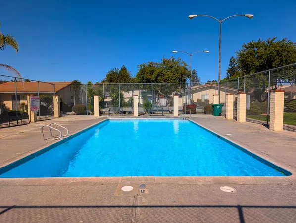 a view of swimming pool with lawn chairs under an umbrella
