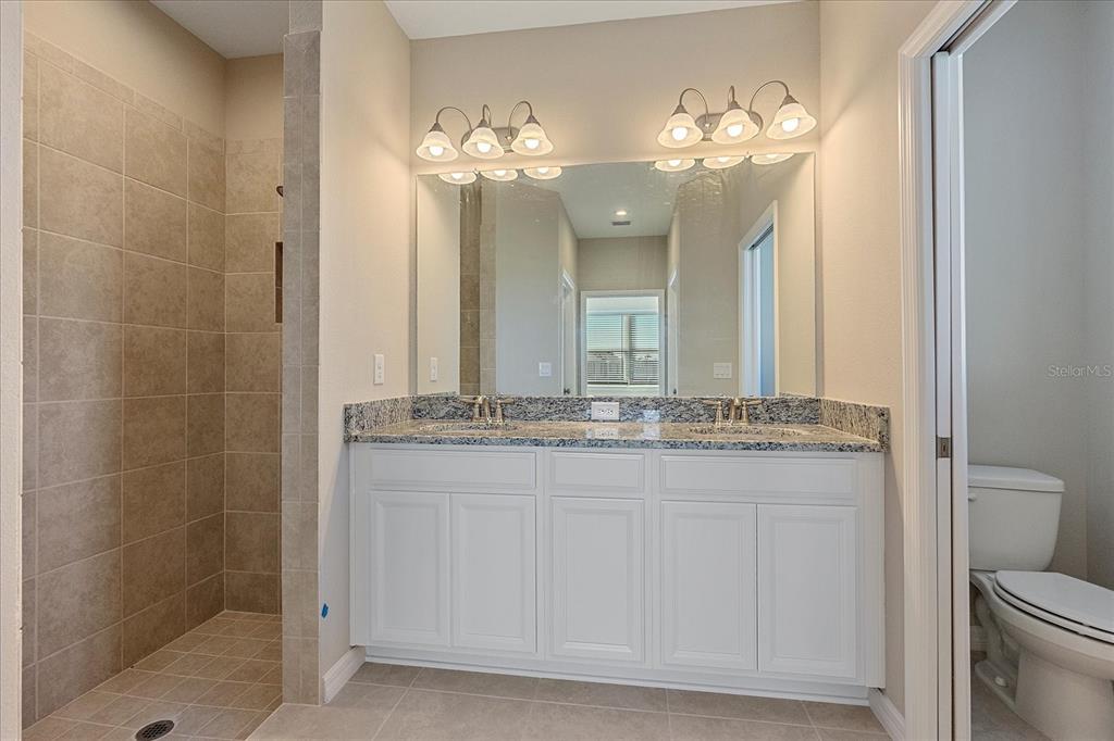 12410 Osorio Court, Unit 201 Sarasota, FL 34238 - Photo 13 of 42 a bathroom with a granite countertop sink a toilet and a mirror