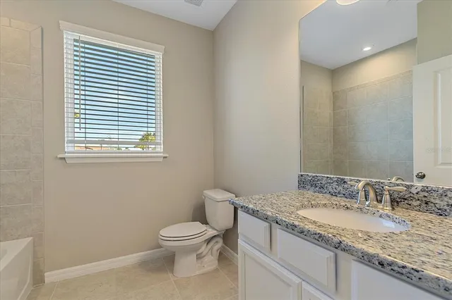 a bathroom with a granite countertop toilet a sink and a mirror