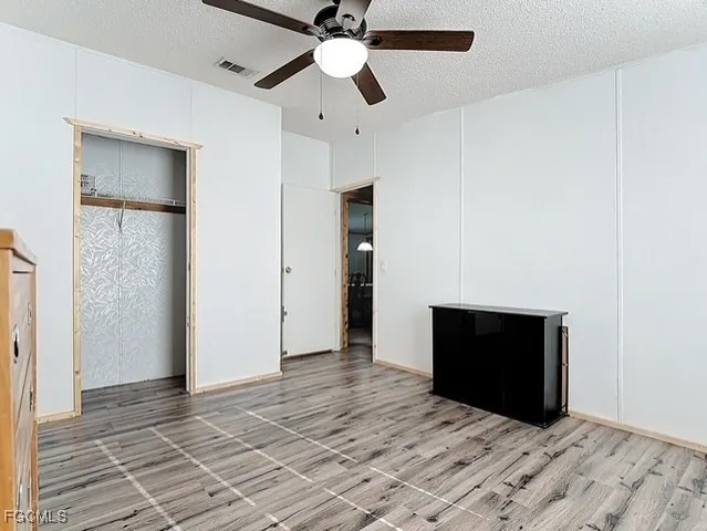 a view of an empty room with a fireplace and a ceiling fan
