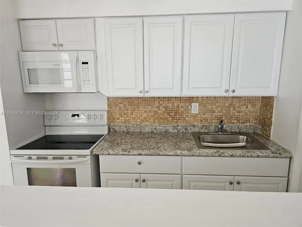 a kitchen with white cabinets and sink