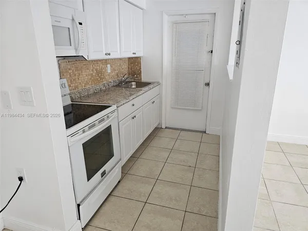 a kitchen with granite countertop a stove a microwave and a sink