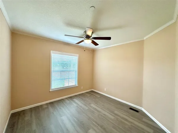 an empty room with wooden floor and ceiling fan