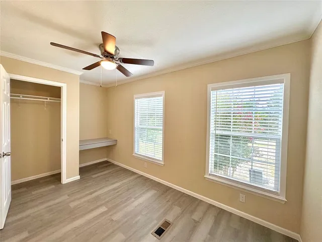 a view of an empty room with a window and wooden floor
