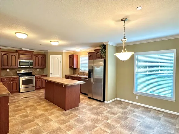 a view of a kitchen with stainless steel appliances kitchen island granite countertop a refrigerator and a stove top oven