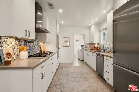 a large kitchen with stainless steel appliances granite countertop a sink and cabinets