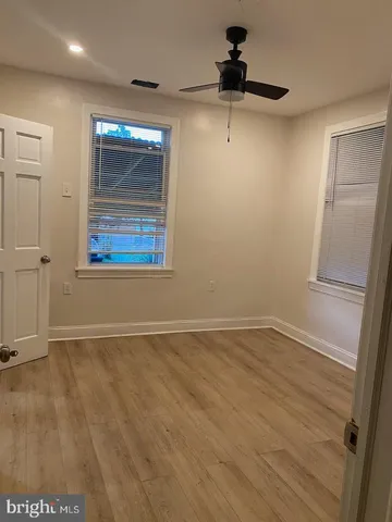 an empty room with wooden floor cabinet and ceiling fan