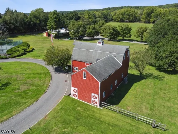 an aerial view of a house with pool big yard and large trees