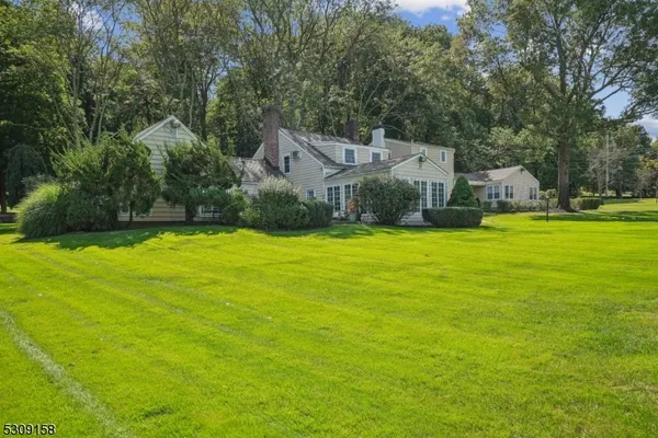 a view of a house with a big yard and large trees