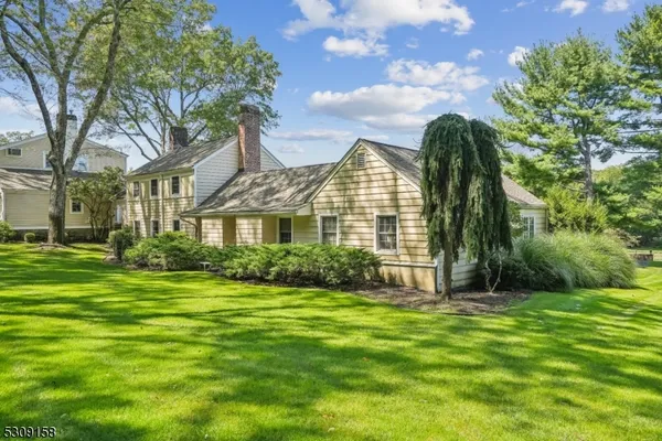 a view of a house with a big yard and large trees