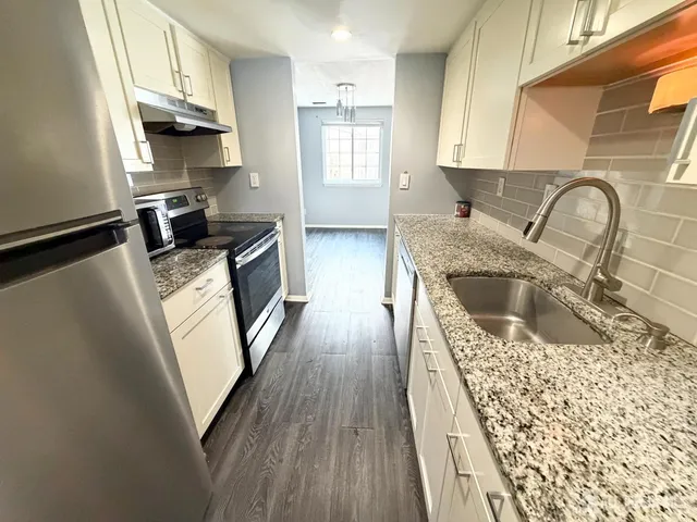 a kitchen with granite countertop a sink a counter space cabinets and stainless steel appliances