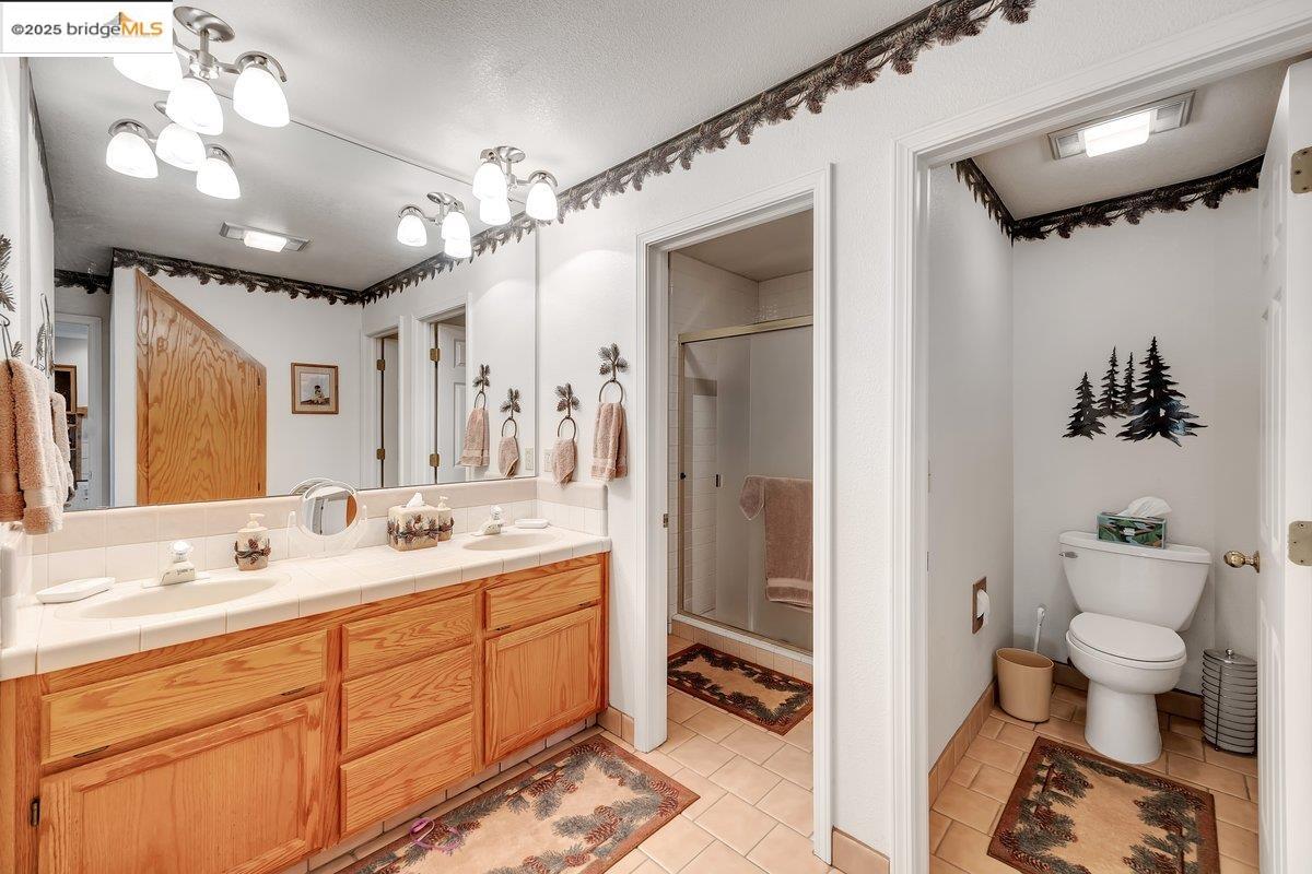 13700 Clements Road Groveland, CA 95321 - Photo 38 of 93 Full bathroom featuring double vanity, light tile patterned floors, and a shower stall