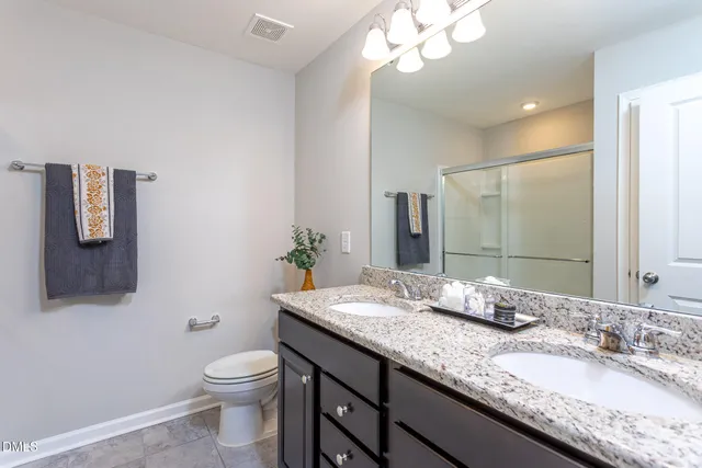 a bathroom with a granite countertop sink a toilet and mirror