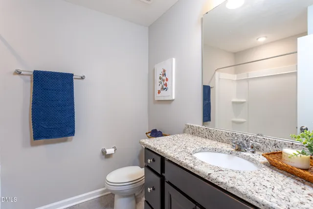a bathroom with a granite countertop sink a toilet and a mirror