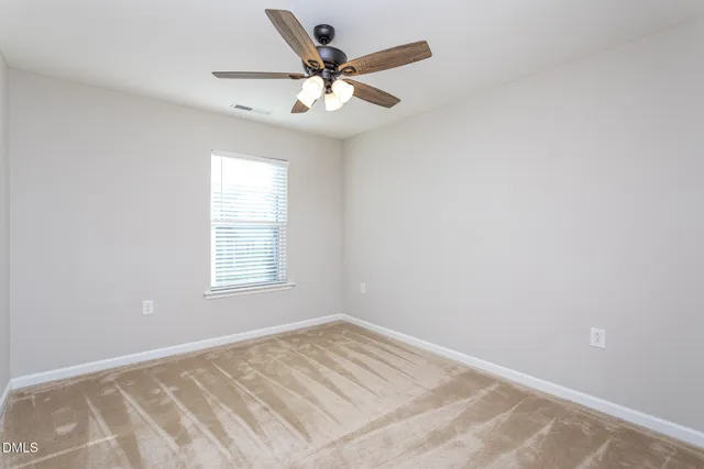 an empty room with a window and a fan