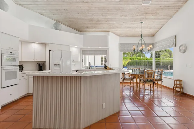 an open kitchen with granite countertop a stove a sink a dining table and chairs with wooden floor