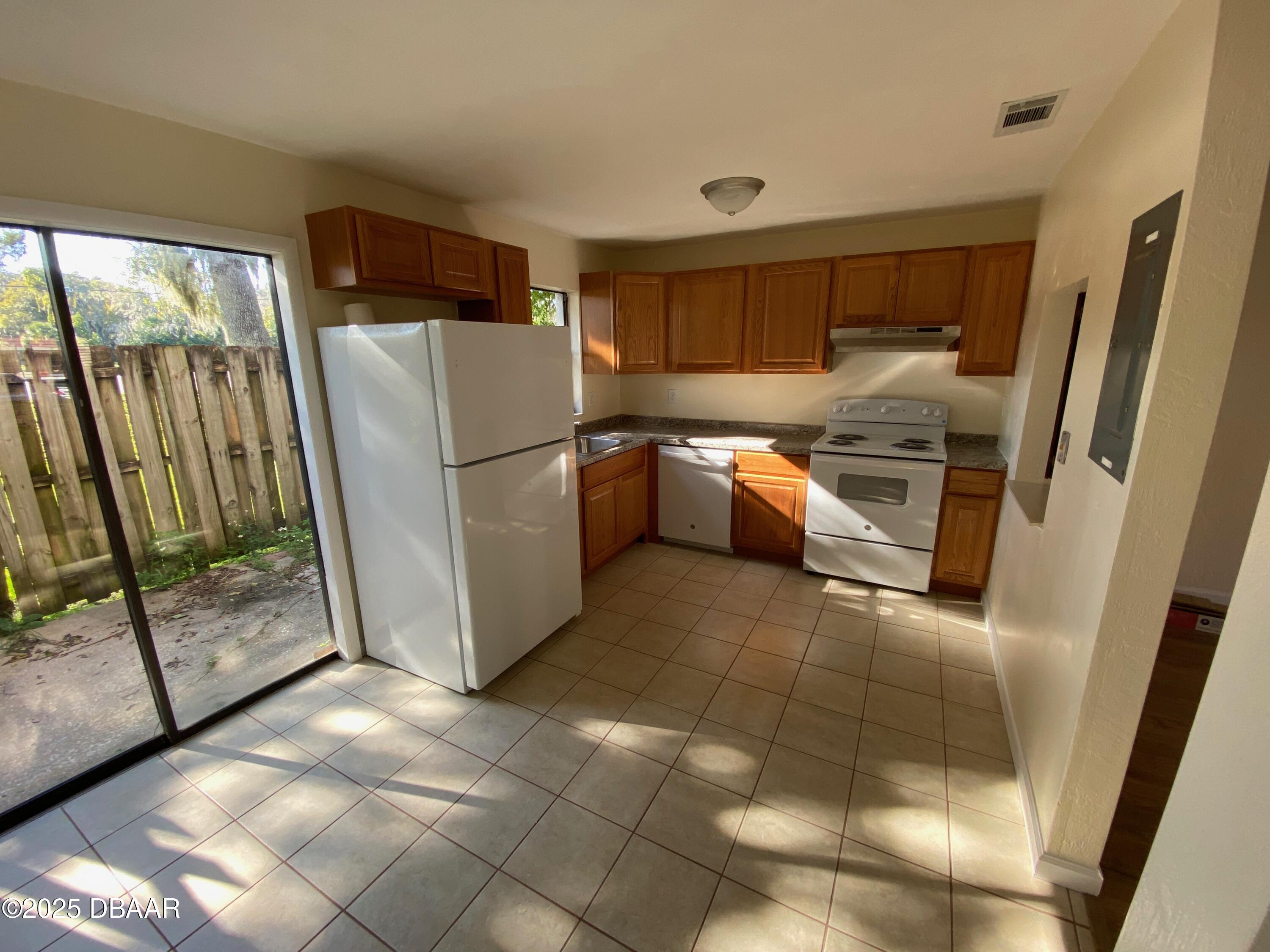 980 Canal View Boulevard, Unit E5 Port Orange, FL 32129 - Photo 2 of 10 a kitchen with a refrigerator and white cabinets