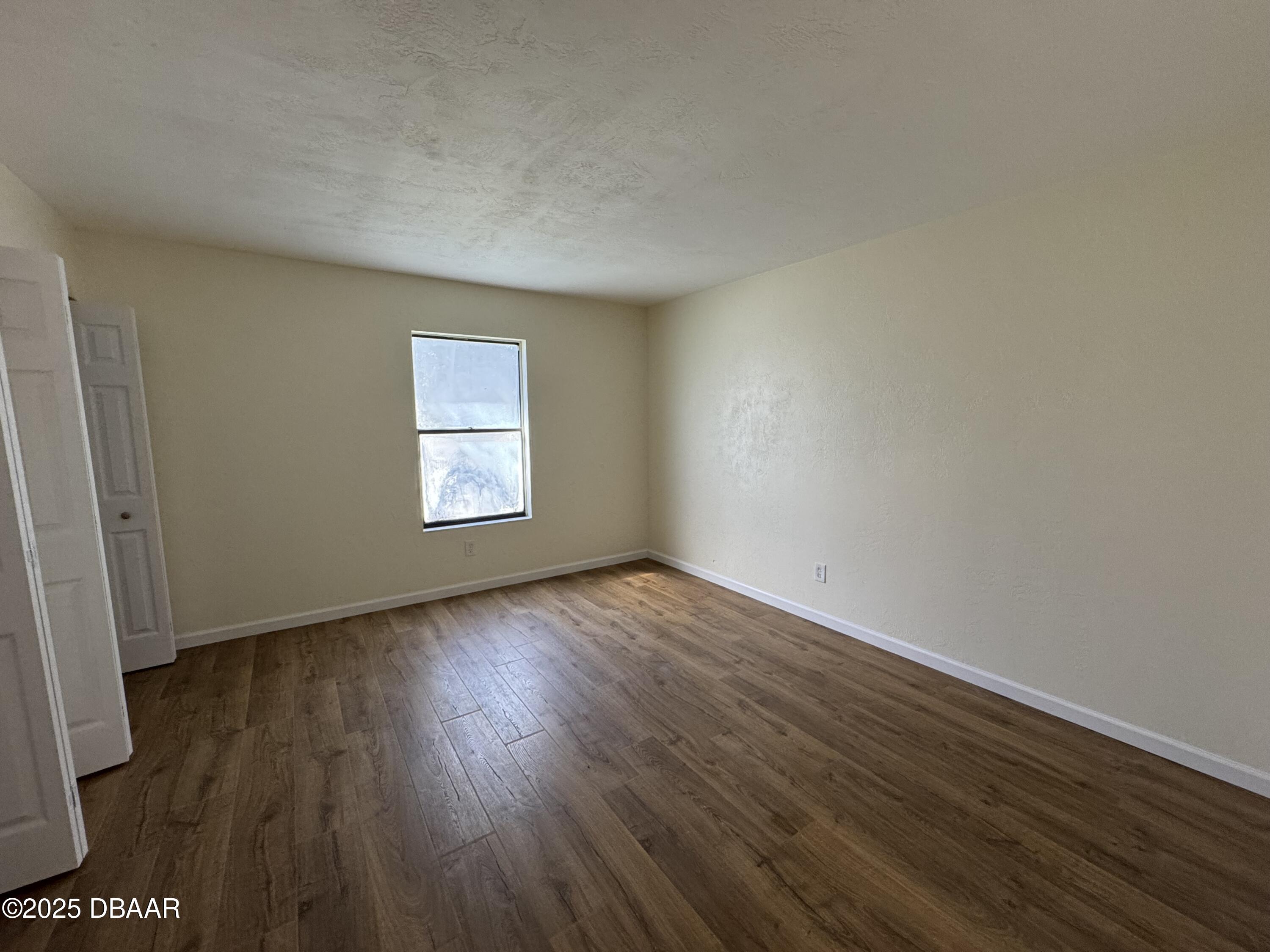 980 Canal View Boulevard, Unit E5 Port Orange, FL 32129 - Photo 5 of 10 an empty room with wooden floor and windows
