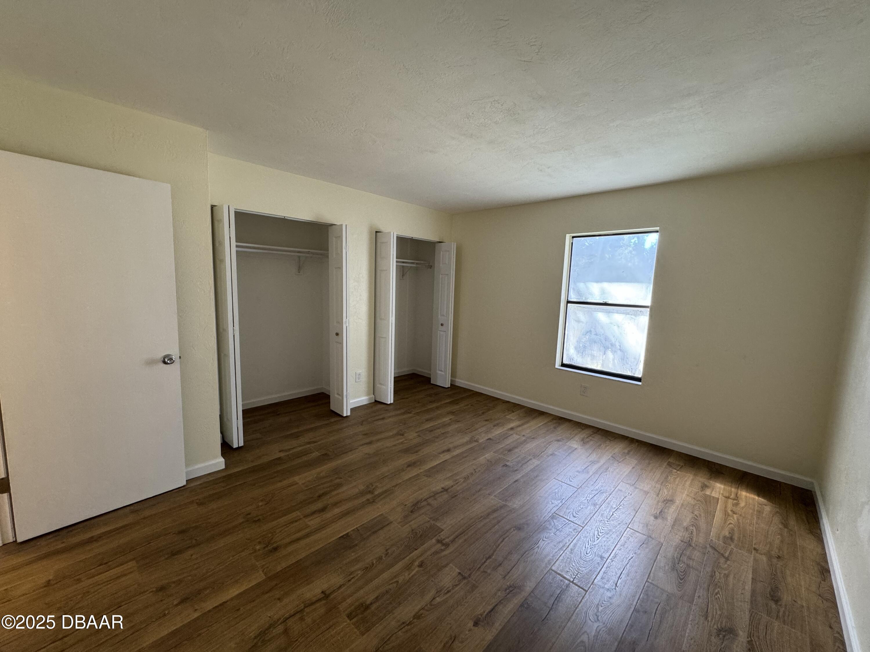 980 Canal View Boulevard, Unit E5 Port Orange, FL 32129 - Photo 6 of 10 an empty room with wooden floor and windows