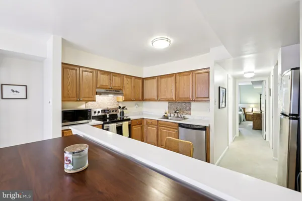 a kitchen with a refrigerator a stove top oven a sink a dining table and chairs
