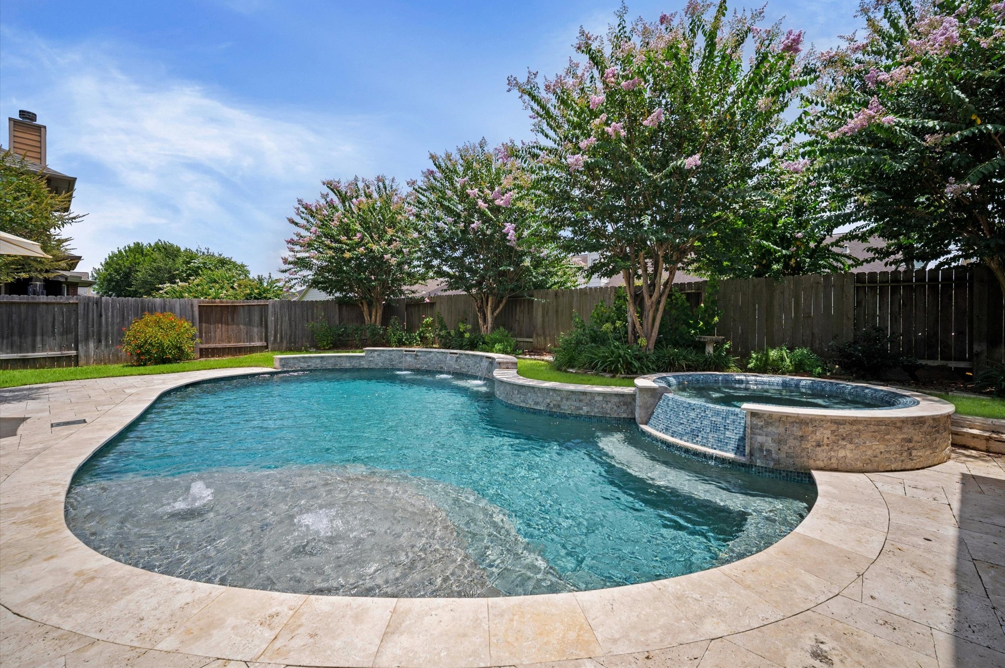 9507 Empress Crossing Drive Spring, TX 77379 - Photo 40 of 50 This photo showcases a spacious backyard with a beautiful swimming pool and adjacent hot tub, surrounded by lush greenery and mature trees, offering a private oasis for relaxation and entertainment.